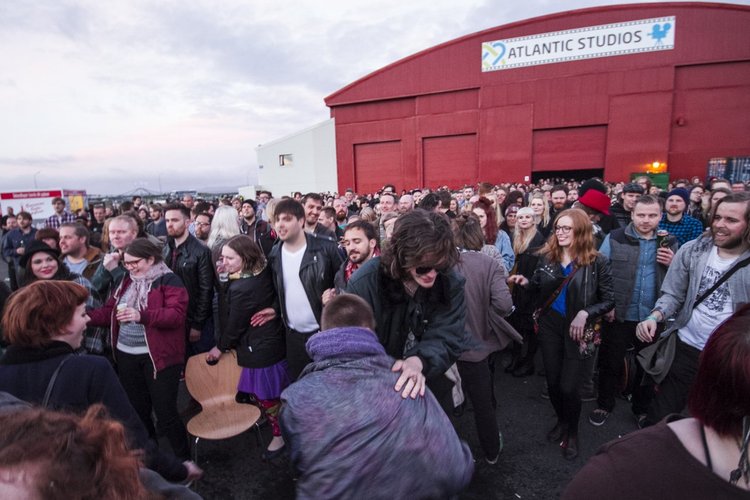 Crowd of people outside Atlantic Studios, some smiling and enjoying the event during sunset.