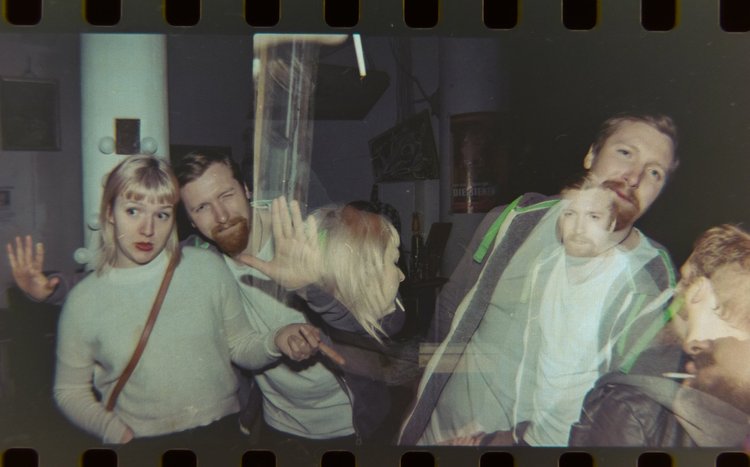 Group of people at a bar or club, some smiling and some making playful expressions.
