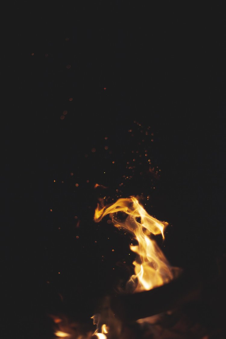 Close-up of a fire with flames and sparks against a dark background.