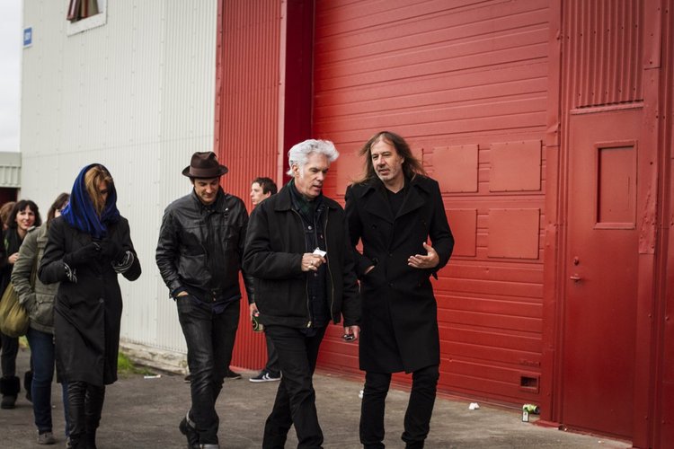 Group of people walking outside near a red building, engaged in conversation.